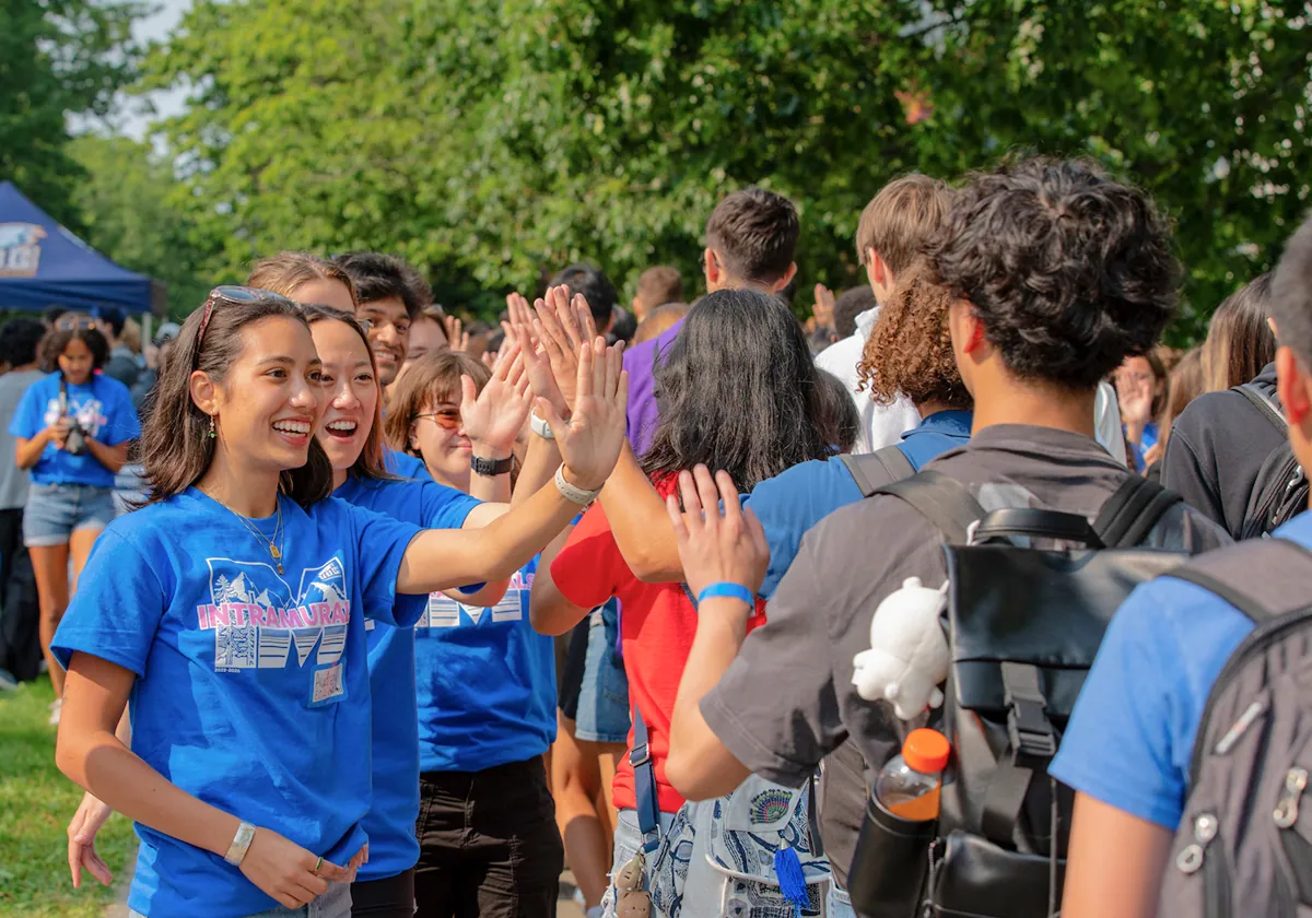 Two student volunteers wearing blue UBC Intramural t-shirts high-fiving students on Imagine Day.