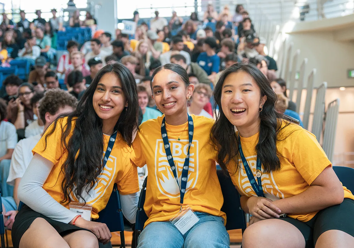 Three smiling female students wearing yellow UBC t-shirts at Imagine Day.