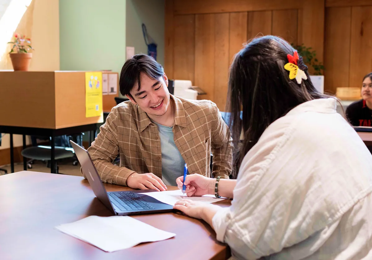 Two students in a classroom reviewing homework together.